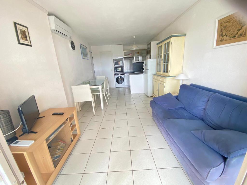 un salon avec un canapé bleu et une cuisine dans l'établissement Appartement 3 Pièces avec Terrasse et Piscine à Saint-Raphaël - FR-1-504-683, à Saint-Raphaël