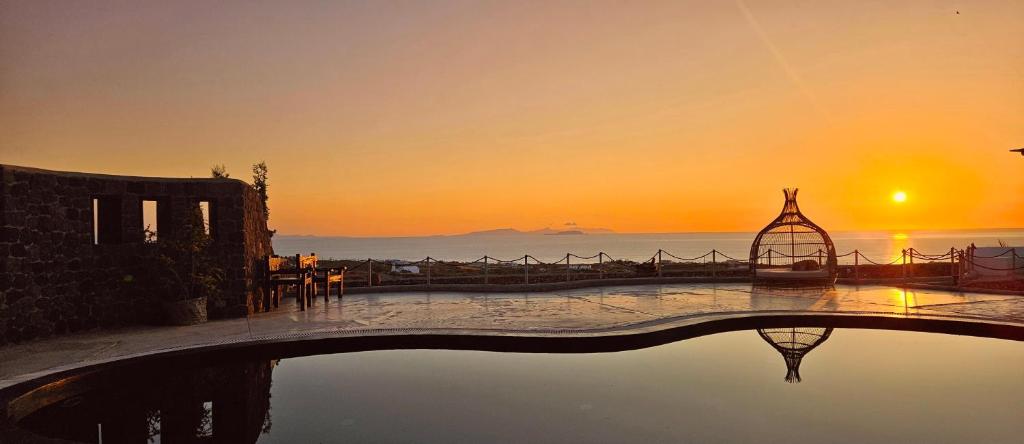 een zwembad met een zonsondergang op de achtergrond bij Thea Luxury Resort in Fira