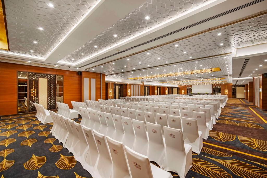 Radisson Blu Hotel GRT, Chennai International Airport في تشيناي: قاعة احتفالات مع كراسي بيضاء في غرفة