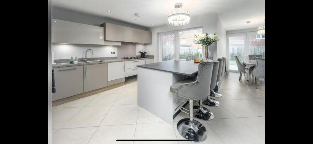 a kitchen with white cabinets and a island with bar stools at Luxury Durham Home in DH1, Free Parking, No Fees in Durham