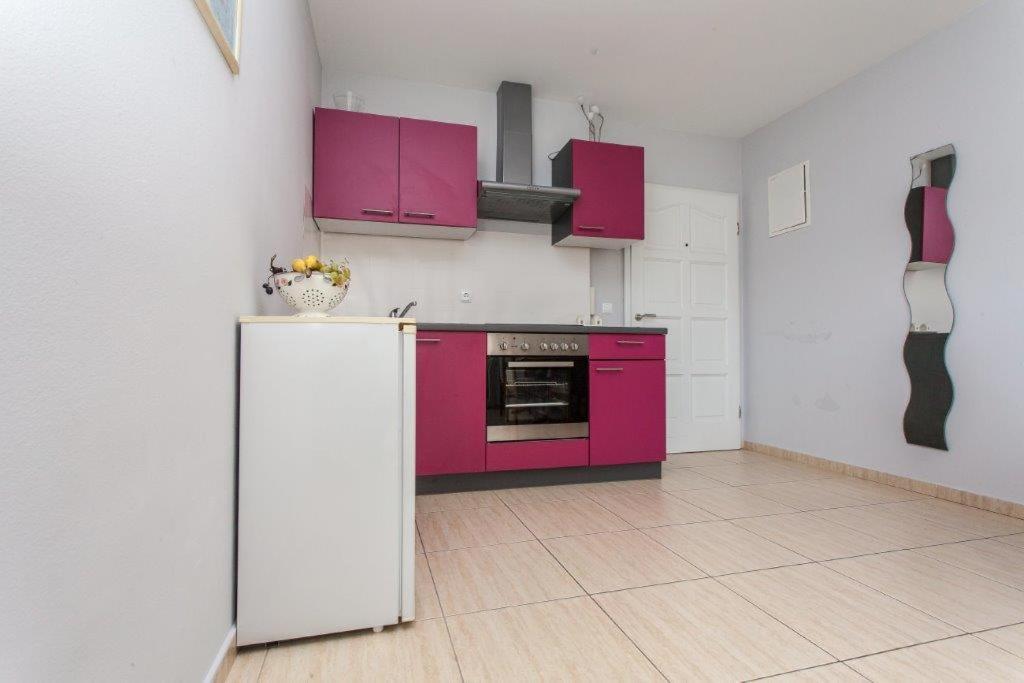 a kitchen with pink cabinets and a refrigerator at Apartment Damir - Novalja in Novalja
