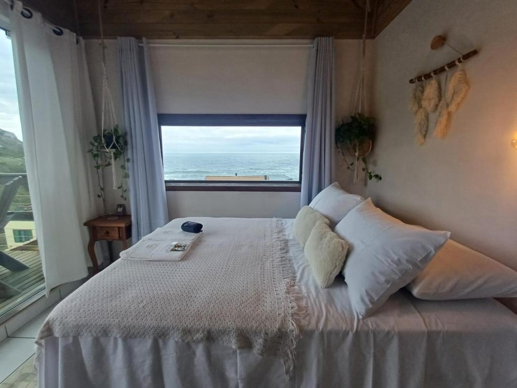 a bedroom with a bed with a view of the ocean at Casa no Farol in Camacho