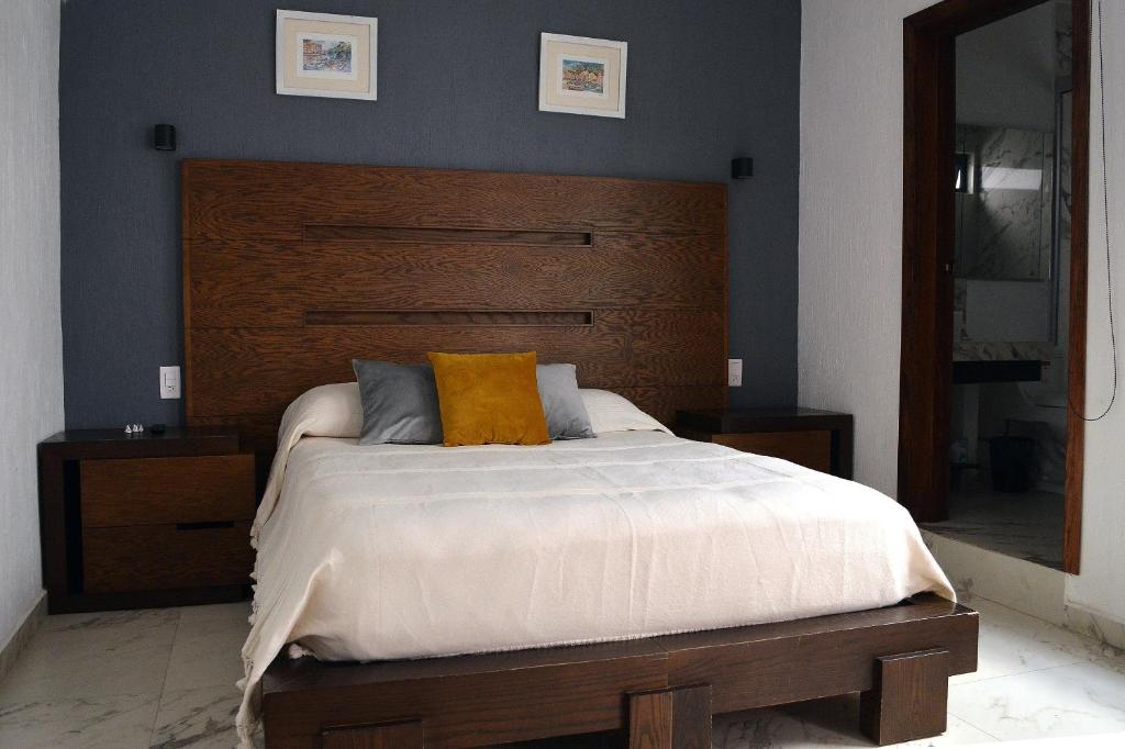 Hotel Casa Gran Plaza, Hermosas y Cómodas Habitaciones en el Corazón de Guadalajara, a bedroom with a large bed with a wooden headboard at Casa Gran Plaza, Hermosas y Cómodas Habitaciones en el Corazón de Guadalajara in Guadalajara