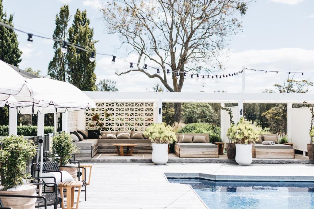 a backyard wedding with a pool and a white pergola at The Oaks Ranch in Tomakin