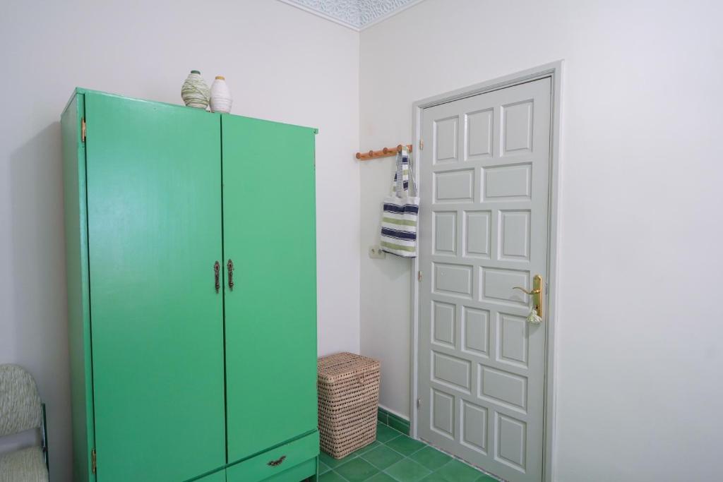a green cabinet in a room with a door at Dar Badr in Tangier