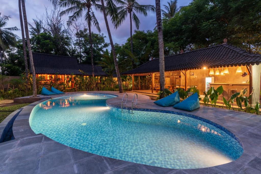 uma piscina com almofadas azuis ao lado de uma casa em Tahlia's Villa em Sorongjukung