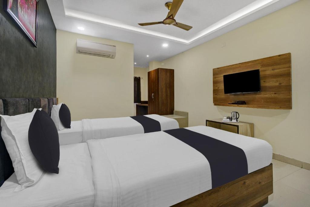 Collection O Hotel Swagath Pride في Mancherāl: غرفة نوم بسريرين بيض وتلفزيون بشاشة مسطحة