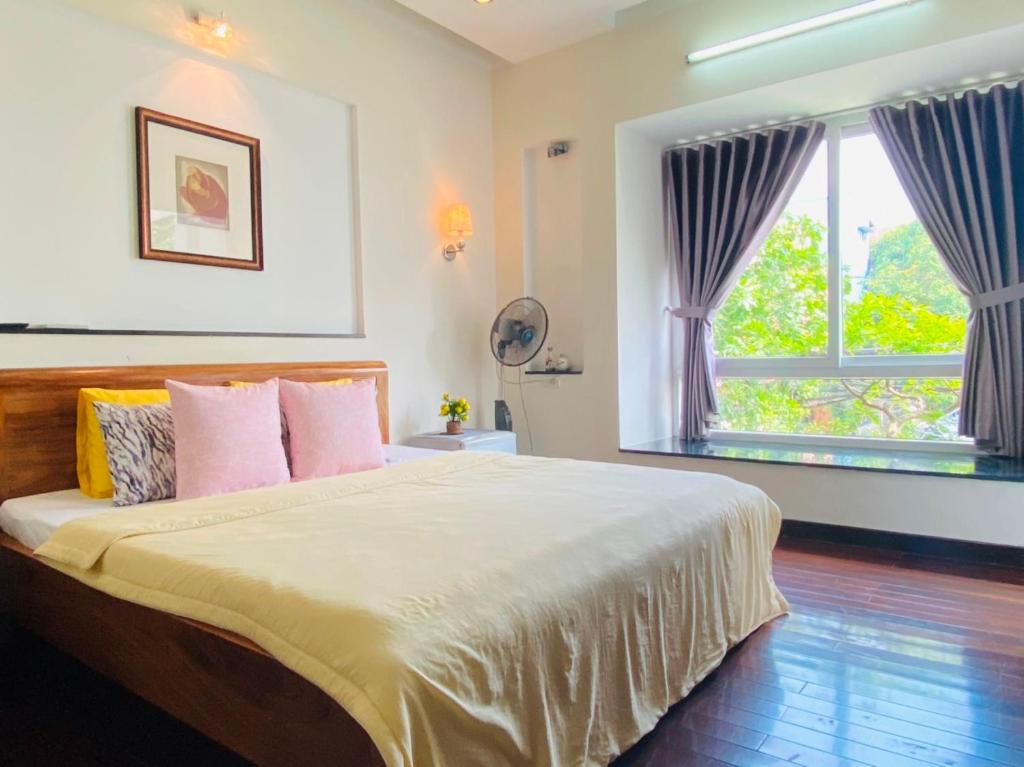 a bedroom with a bed with pink pillows and a window at Moon Homestay Huế in Thôn Dương Xuân Hạ