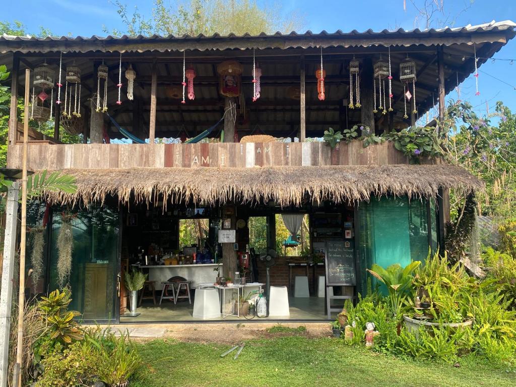a building with a straw roof with a bar in it at i AM i Farm Stay in Mē Tamān