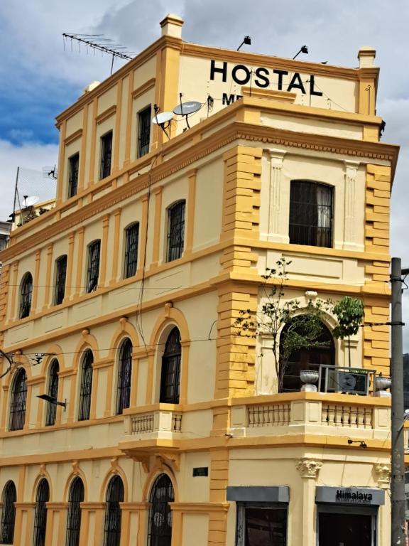 Un edificio amarillo con una señal de hospital. en Hostal Mediodia, en Quito