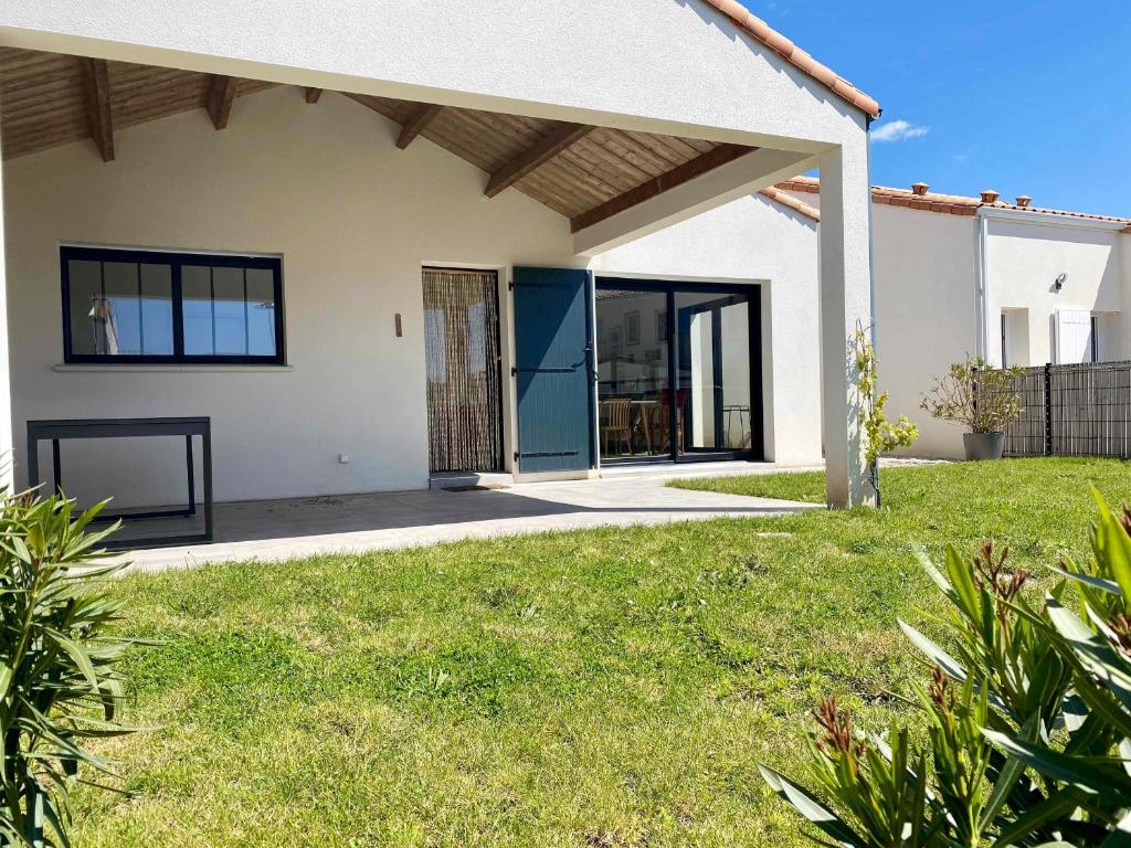 une maison avec une grande porte en verre dans une cour dans l'établissement Maison moderne et charmante à 450m de la plage, 2 chambres, terrasse et barbecue - FR-1-336-153, à Saint-Vincent-sur-Jard