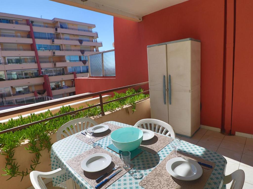 d'un balcon avec une table et des chaises ainsi qu'un réfrigérateur. dans l'établissement Sète: T2 avec terrasse couverte, piscine et parking en résidence front de mer - FR-1-472A-306, à Sète
