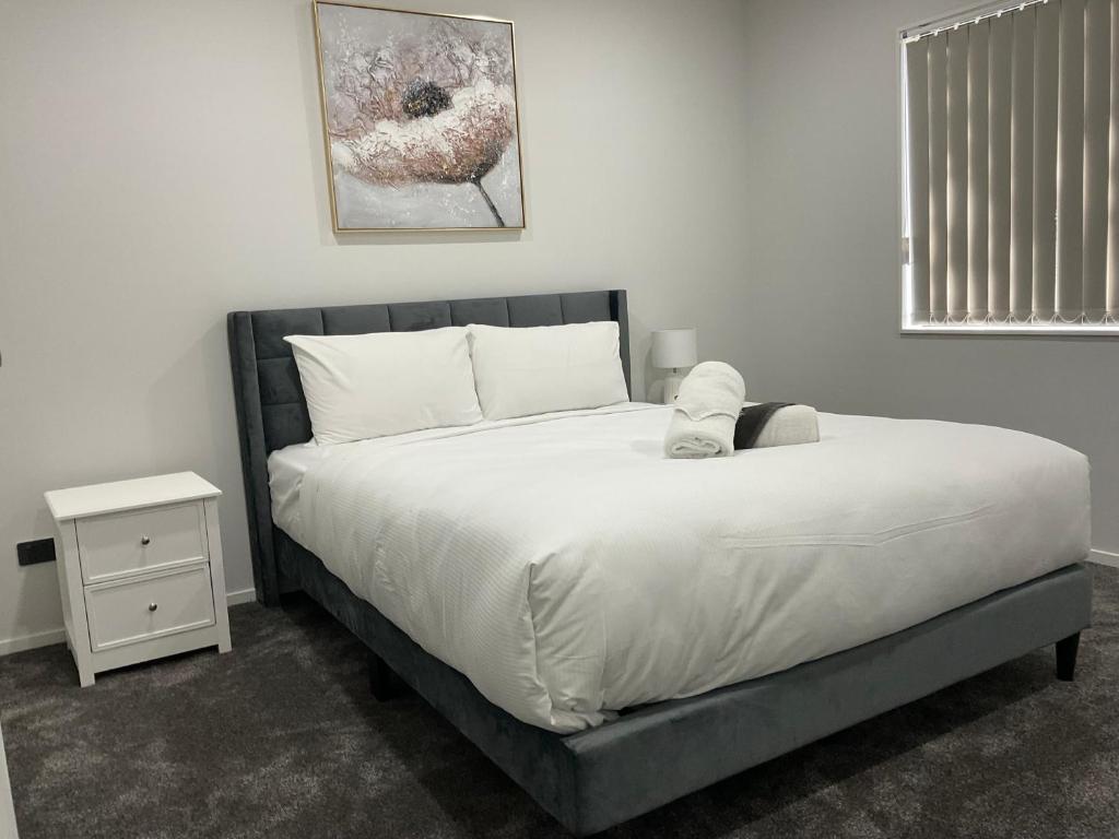 a bedroom with a bed and a nightstand with a white bedspread at Holiday Home or Short term Rental in Papatoetoe in Auckland