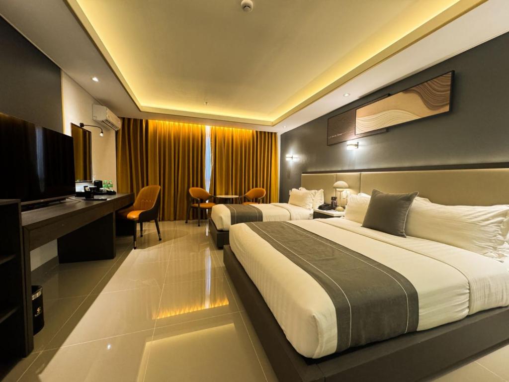 um quarto de hotel com duas camas e uma televisão em Subic Riviera Hotel & Residences em Kababae
