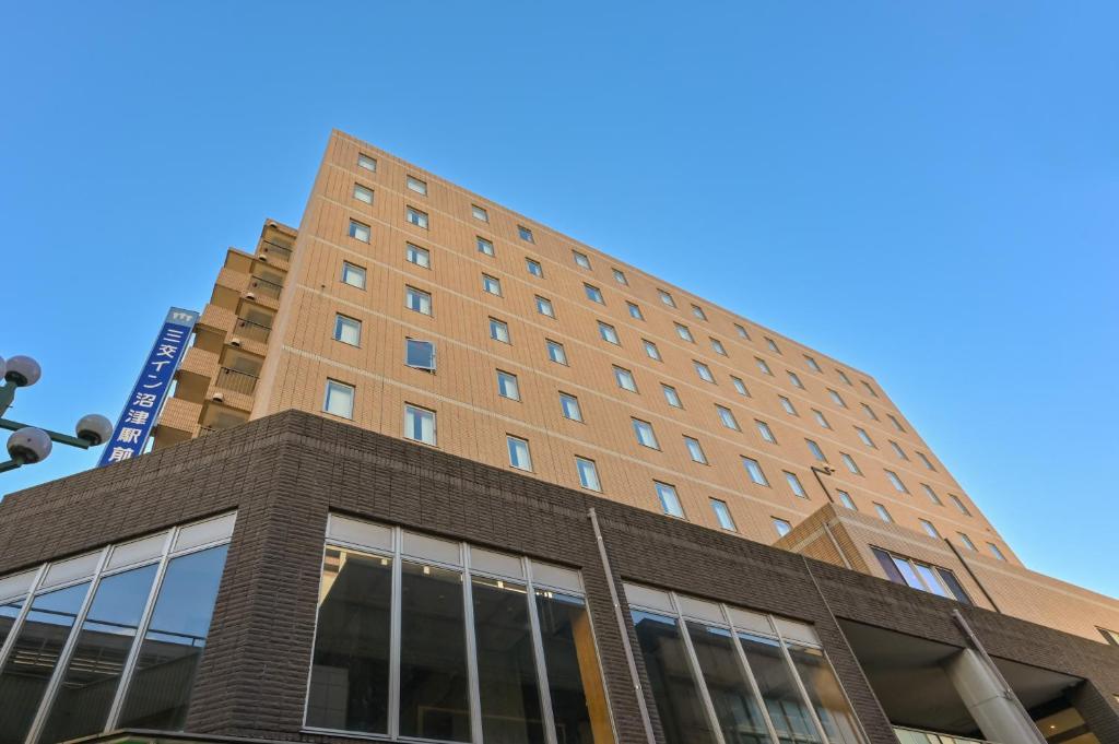 沼津的住宿－沼津站前桑科酒店，一座高大的砖砌建筑,背后是蓝天