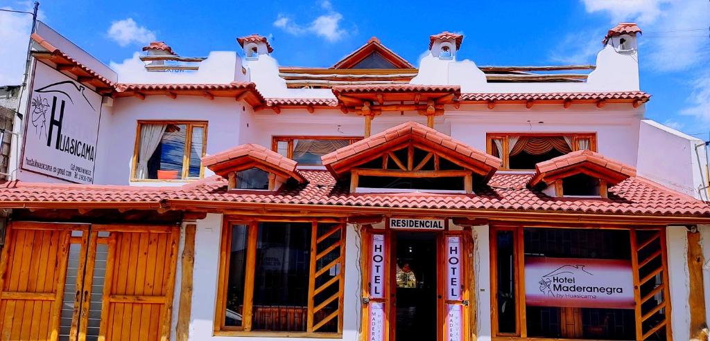 een wit gebouw met een rood dak bij Hotel Maderanegra By Huasicama in Latacunga