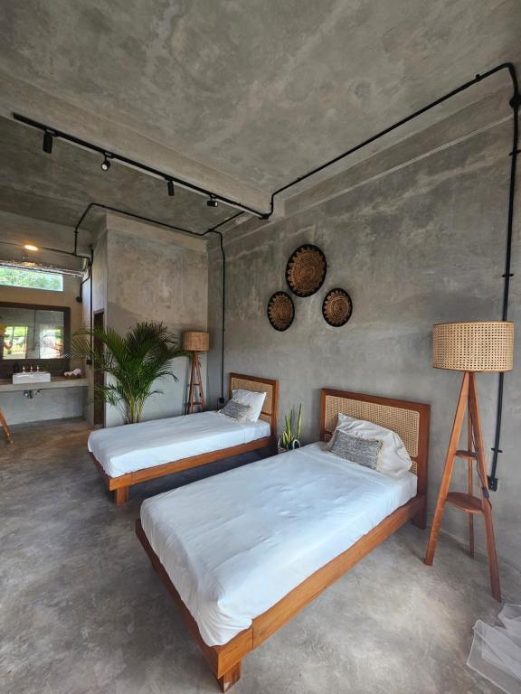 a bedroom with two beds and a lamp at Salty Prana Retreat Center in Uluwatu