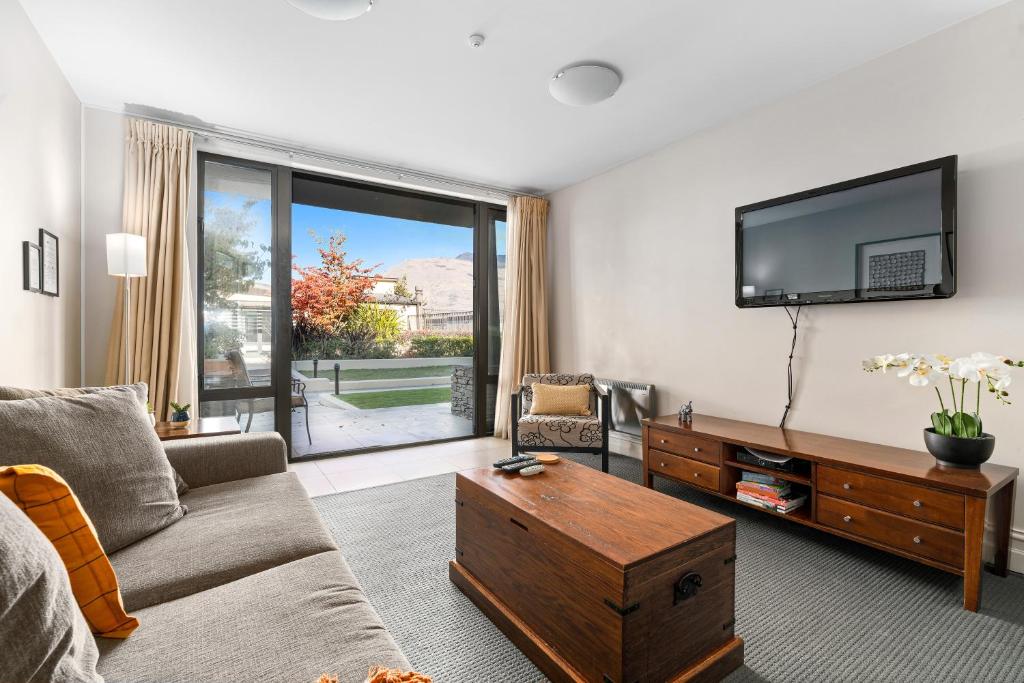 a living room with a couch and a flat screen tv at THE BEACON - 2 BEDROOM TOWN CENTER APARTMENT 614 in Queenstown