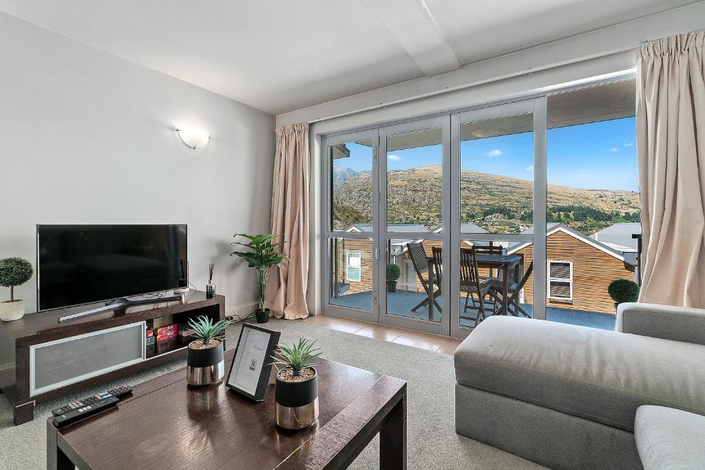 a living room with a couch and a large window at Lakeside Living - Modern 2-Bedroom Apartment in Queenstown