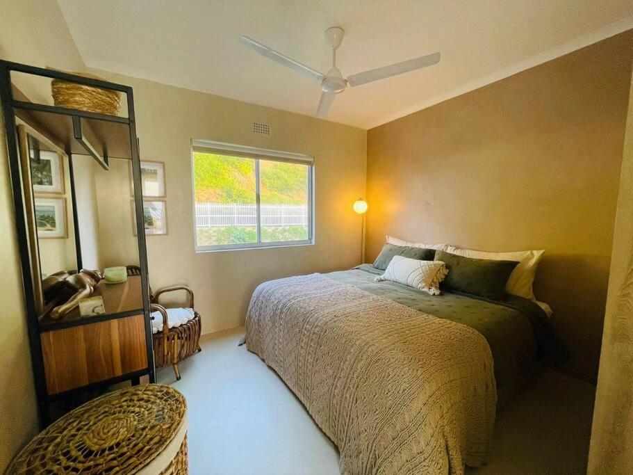 a bedroom with a bed and a mirror and a window at Chic Bohemian Hideaway in Umdloti