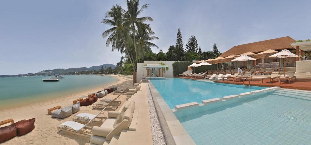 a swimming pool with lounge chairs and a beach at Chi Samui Resort in Bophut
