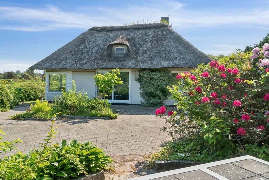 a small house with a thatched roof in a garden at Cozy Farmhouse With Fantastic Surroundings, in Farsø