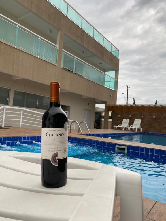 a bottle of wine sitting on a table next to a swimming pool at Pousada e Espaco AURORA Peruibe in Peruíbe