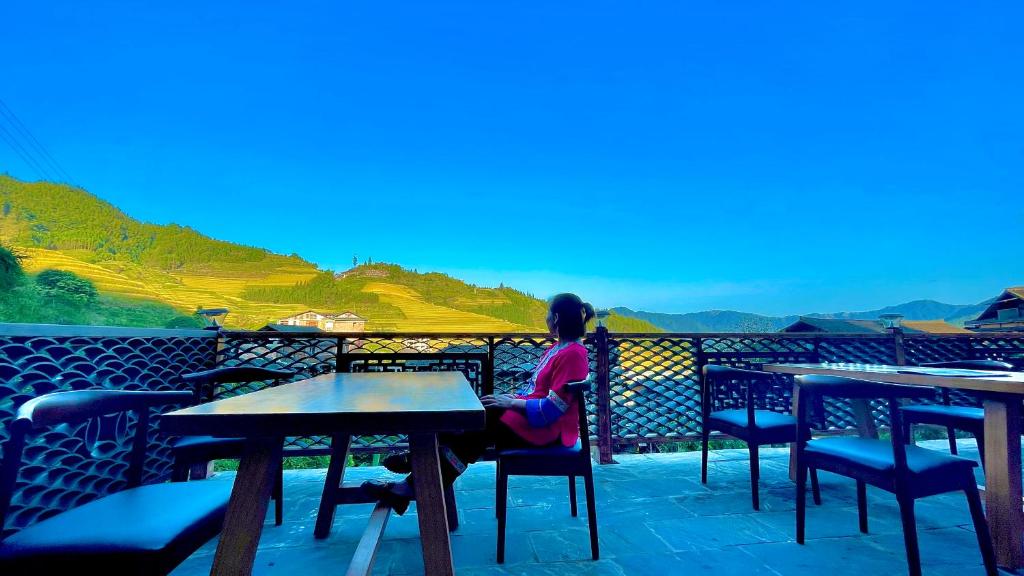 een vrouw aan een tafel op een balkon bij 麦田间民宿Terrace View Hotel in Longsheng