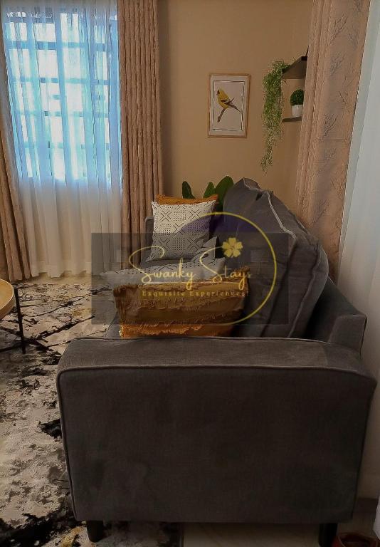 a grey couch with a glass table in a living room at Swanky Stays I in Nairobi