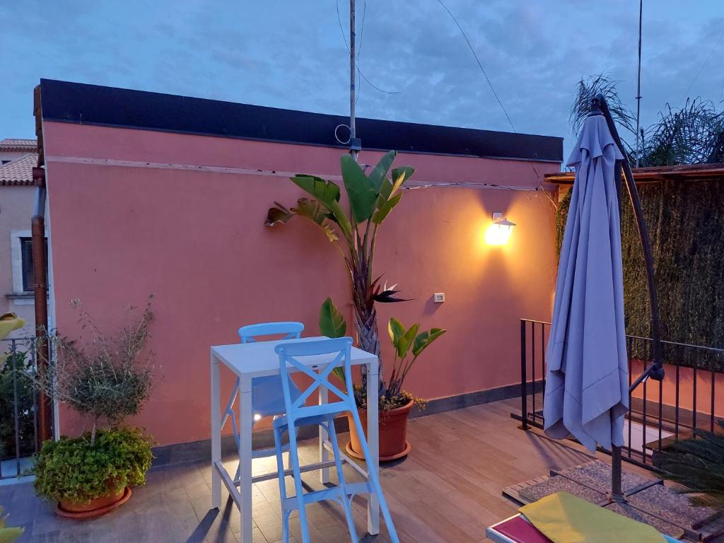 eine Terrasse mit einem Sonnenschirm, einem Tisch und einem Stuhl in der Unterkunft Galena Charme Luxury Terrace in Syrakus