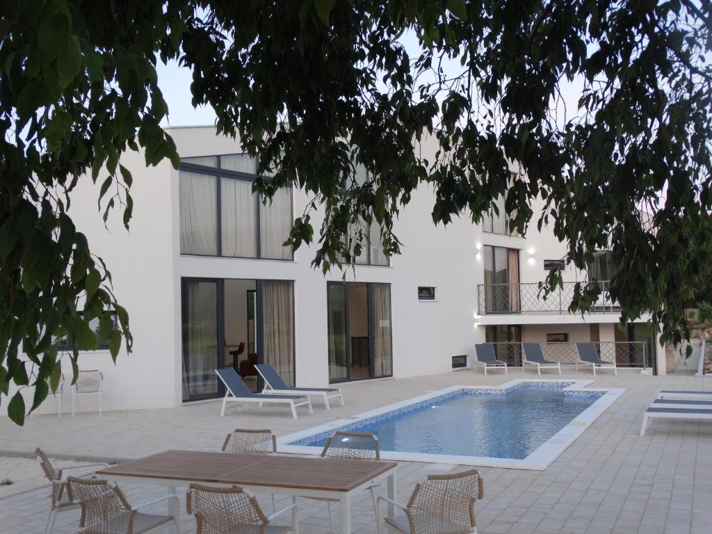Un edificio con piscina, mesas y sillas. en Villa Bagulina, en Drniš