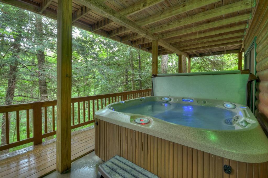 a jacuzzi tub on the deck of a cabin at K6 Lodge Gather around the firepit soak in the hot tub and splash in the creek in Blue Ridge