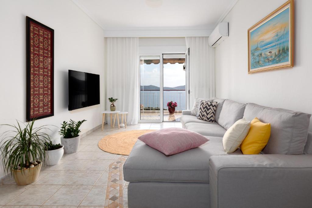 a living room with a couch and a tv at Mimoza's Sea View Apartment in Paleo Tsifliki
