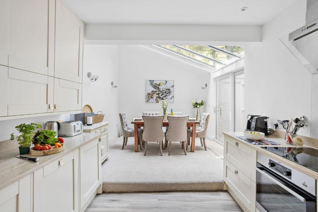 a kitchen with white cabinets and a table with chairs at 10 Clarence Hill - Elegant Town House with outside space in Dartmouth