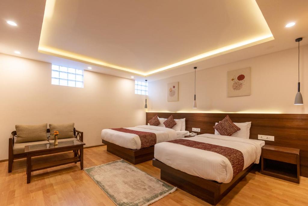 a hotel room with two beds and a couch at Apex Business Hotel in Kathmandu