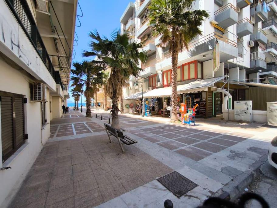 a empty street with palm trees and a bench at Apartment 50 meters from the beach in Loutraki