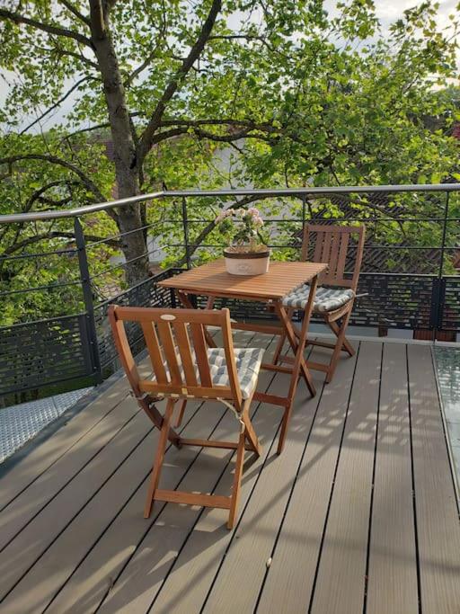 une table et une chaise en bois sur une terrasse en bois dans l'établissement Au gré du tulipier - 2 pièces, à Monswiller