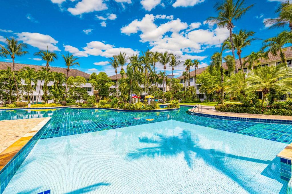 a swimming pool at the resort with palm trees at Boat Lagoon Yacht Marina Hotel in Ban Bang Khu