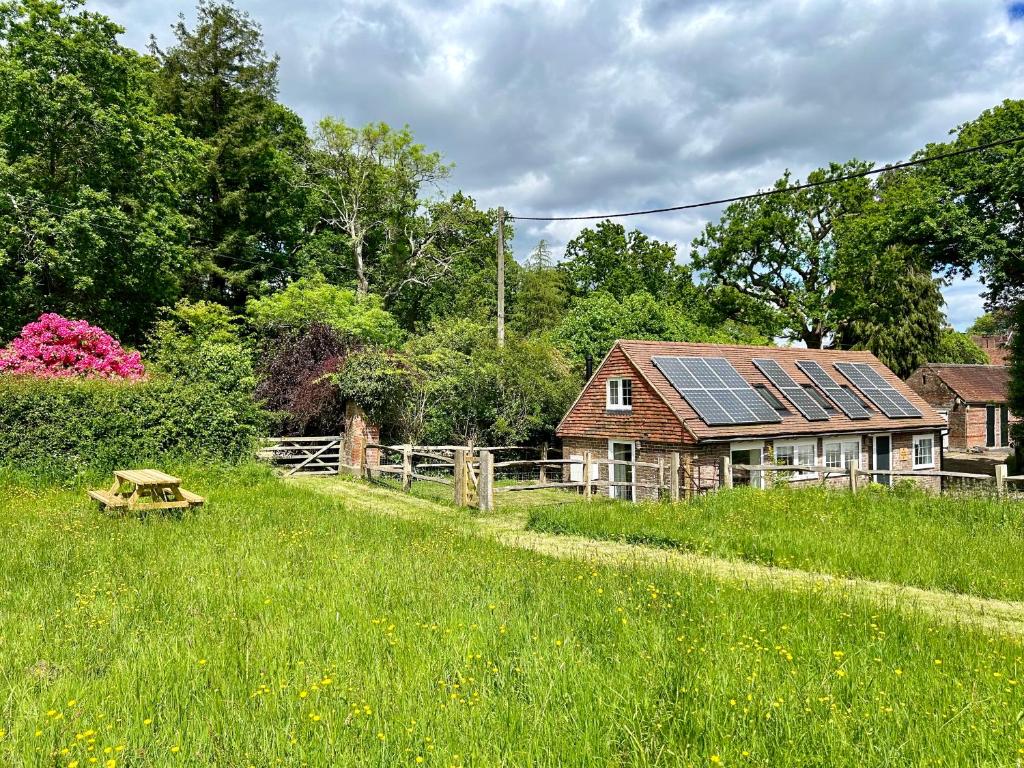 a house with solar panels on top of a field at The Old Workshop, Wadhurst in Wadhurst