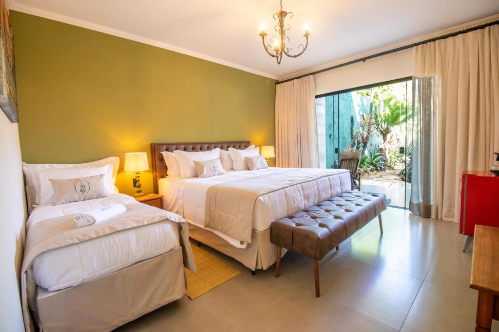 a bedroom with two beds and a large window at Unalome Pousada in Serra Negra