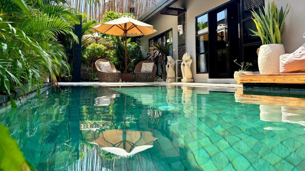 a swimming pool with an umbrella in a house at Amalika Private Pool Villa Central to Everything in Gili Trawangan