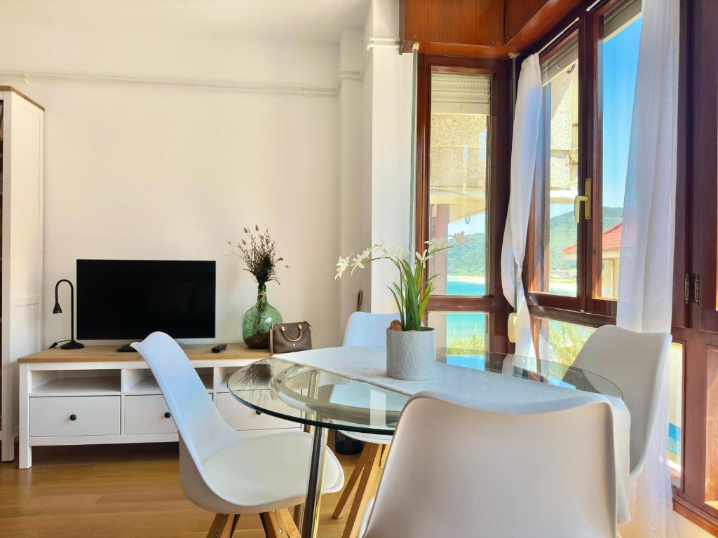 une salle à manger avec une table en verre et des chaises blanches dans l'établissement El Camarote - 6019, à Noja