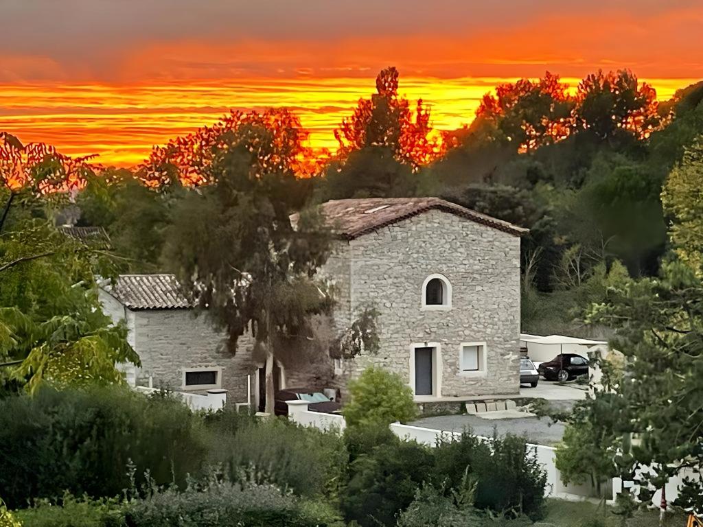 une maison avec un coucher de soleil en arrière-plan dans l'établissement Maison en pierres, à Fontanès