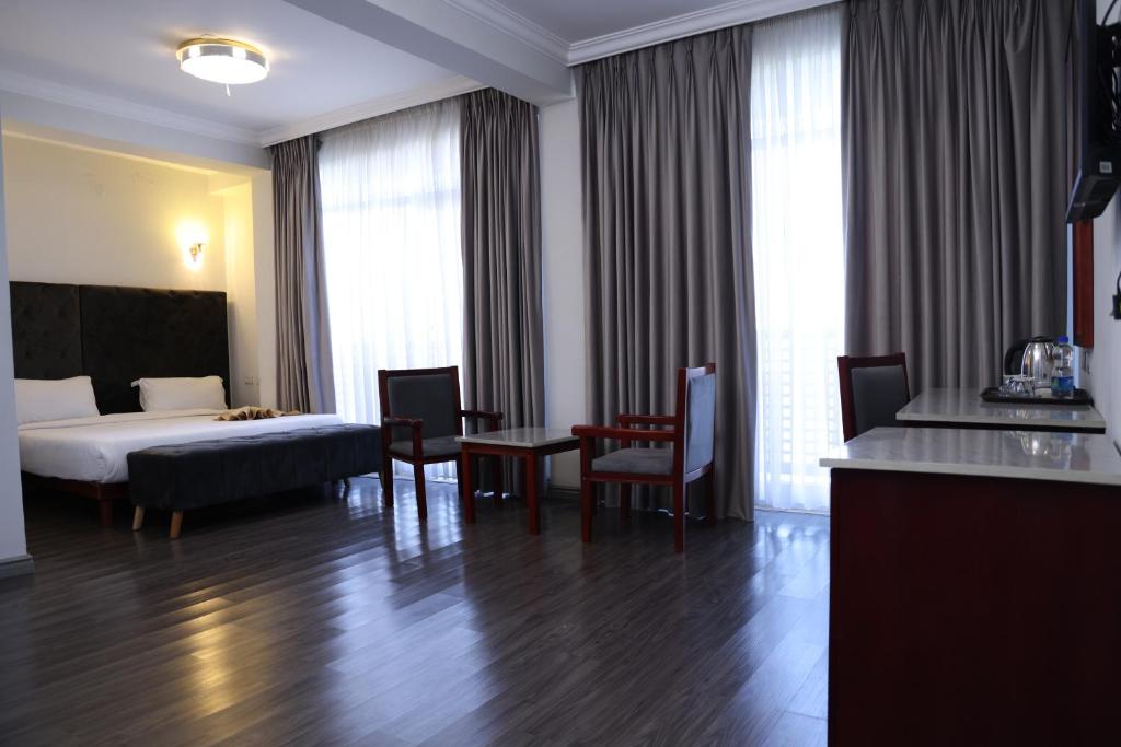um quarto de hotel com uma cama, uma mesa e cadeiras em Trinity Hotel em Addis Ababa