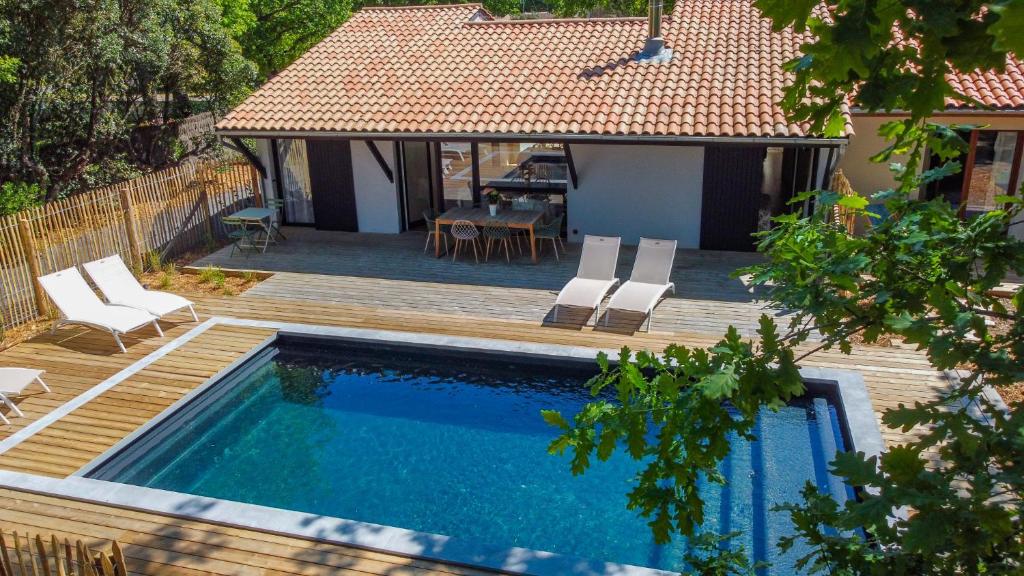 una piscina con terrazza e una casa di EVASION BASSIN La Villa Régate Chambres d'hôtes a Lège-Cap-Ferret