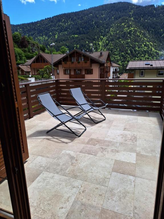 two chairs sitting on a patio with a fence at Casa Bellavista in Molveno