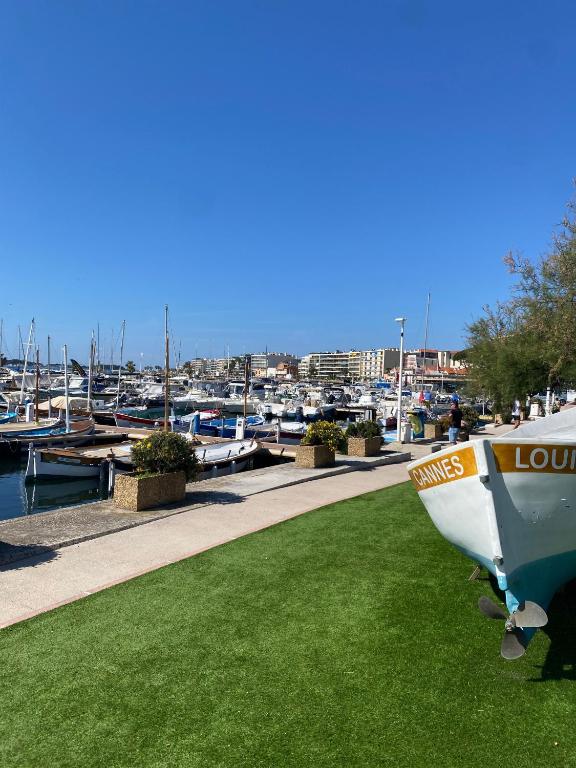 un bateau assis sur l'herbe à côté d'un port de plaisance dans l'établissement Appartement neuf Pointe Croisette, 50 m de la mer, à Cannes