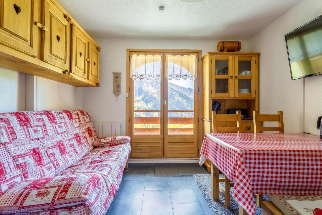 un salon avec un canapé, une table et une fenêtre dans l'établissement L'étoile des Neiges - Studio sur les pistes Manigod, à Manigod