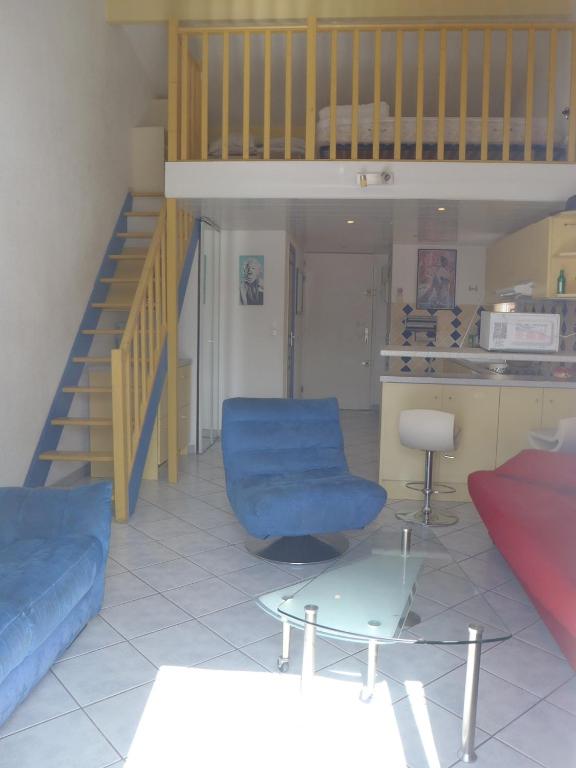 un salon avec un canapé bleu et une table dans l'établissement REF 4060 Joli studio mezzanine climatisé, à Le Castellas