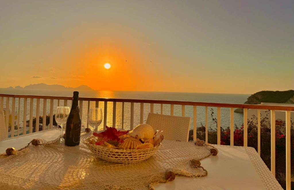 Ponza Vista Mare في بونسا: طاولة مع سلة من الطعام وزجاجة من النبيذ
